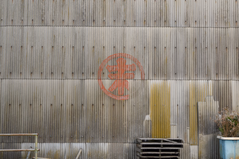 A rusty metal building with a logo on it.