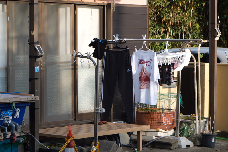 A photo of a clothes drying rack with clothes hanging on it, a pair of pants, a t-shirt, and a basket of clothes.
