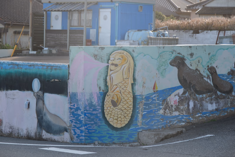A mural on a wall depicting a lion, sea animals, and a traditional Japanese-style lion, with a modern touch.