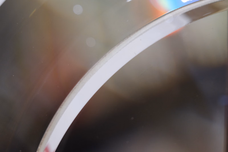 A close-up, blurry shot of a curved lens surface showing internal reflections and light flares.