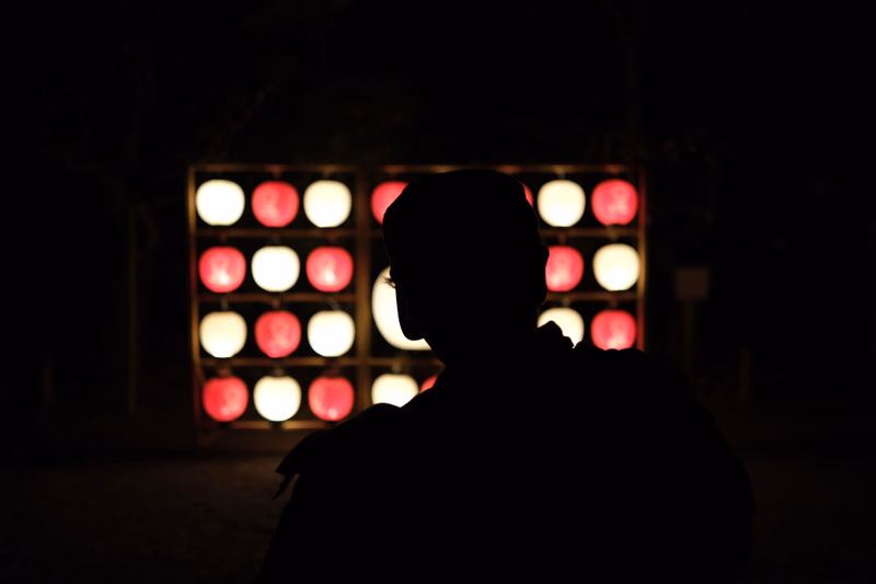 A person is silhouetted against a background of bright, colorful lights at night.