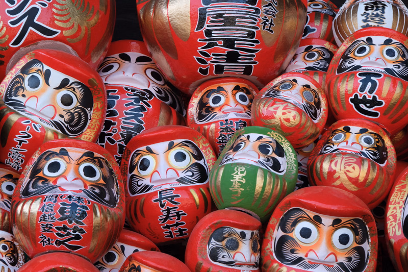 A close-up collection of colorful, traditional Japanese festival masks, some featuring legible text like "皇冠".