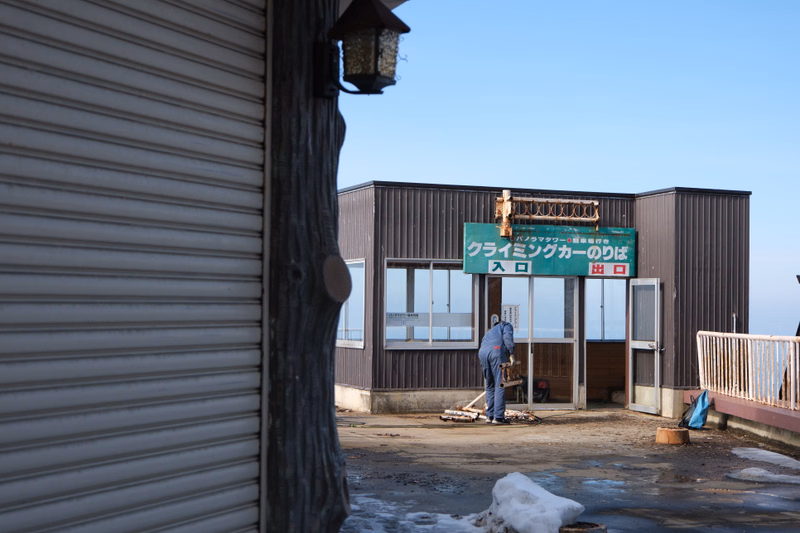 A sign for "クライミングカーのりば" is visible on the exterior of a modern building under a clear sky.