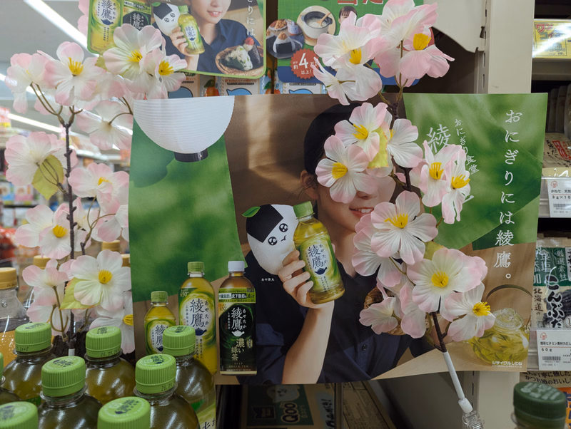 A colorful advertisement featuring cherry blossoms and various products, including bottles labeled with Japanese text.