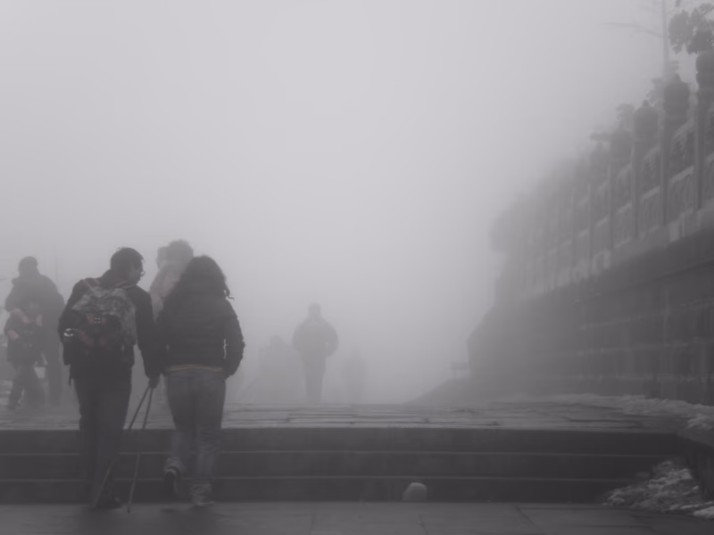 A foggy day in Suishan, Sichuan, China. Two people are walking up a set of stone steps, surrounded by a thick mist.