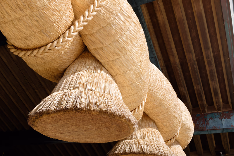 A close-up of a traditional woven basket hanging from a wooden structure in a traditional Japanese setting.