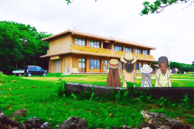 Several children wearing straw hats stand in a grassy yard in front of a large wooden house on an overcast day.