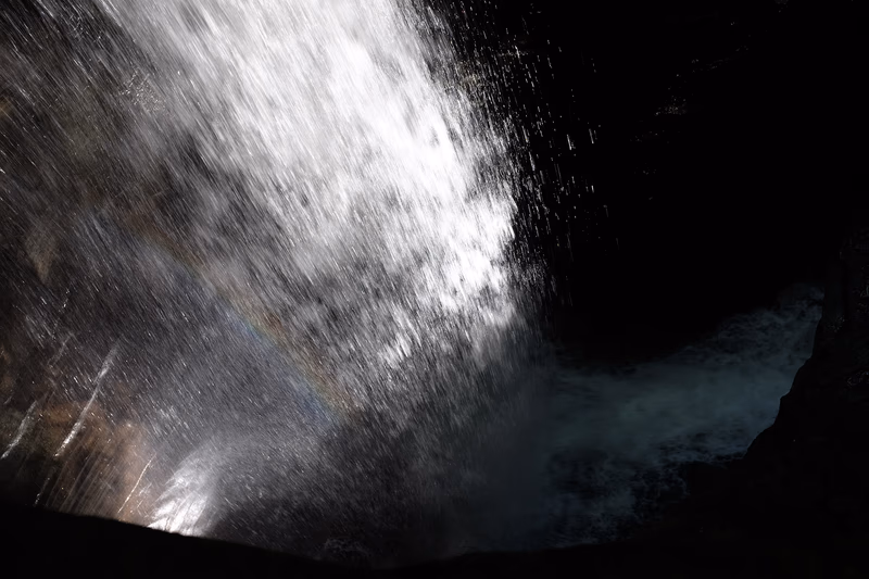 A dramatic waterfall in a dark cave with a beam of light piercing through the water