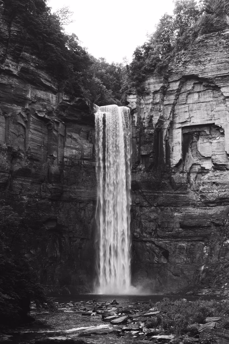 A black and white photograph of a waterfall cascading down a rocky cliff.