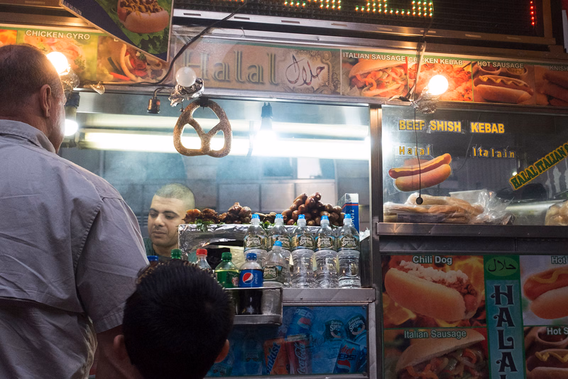 A food stall displaying various items like "CHICKEN GYRO" and "ITALIAN SAUSAGE" on its menu board.
