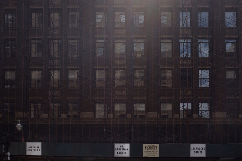 A tall, dark commercial building facade features multiple windows and ground-level signs for "ALLEN M JEWELERS", "MR. BROADWAY KOSHER", "EVEREST", and "STARBUCKS COFFEE".