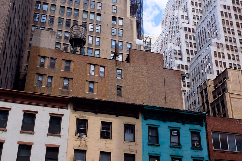A collection of multi-story apartment buildings in a dense urban setting, featuring various architectural styles and materials.