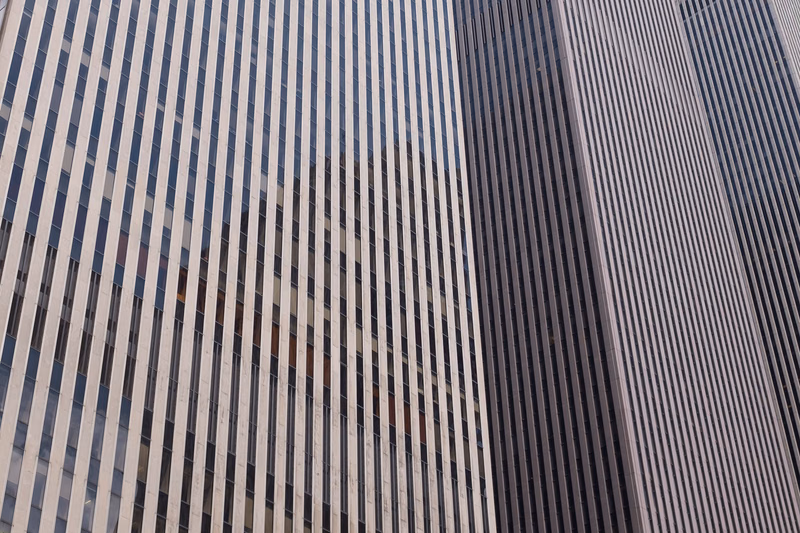 A close-up view of a modern skyscraper facade featuring vertical lines of windows and concrete paneling.