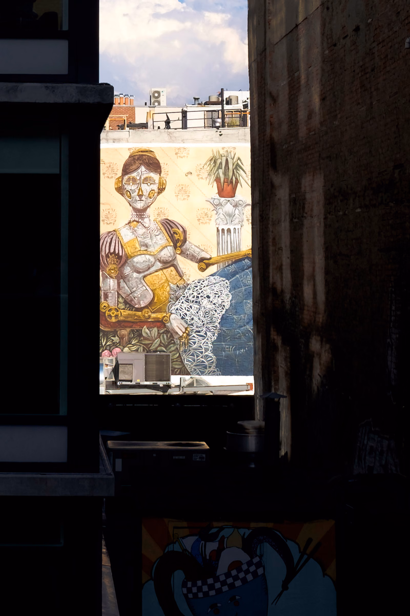 A colorful mural depicts a stylized woman with golden armor and a potted plant in the background.