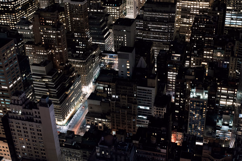 A dense nighttime cityscape view showing numerous illuminated high-rise buildings in an urban area.