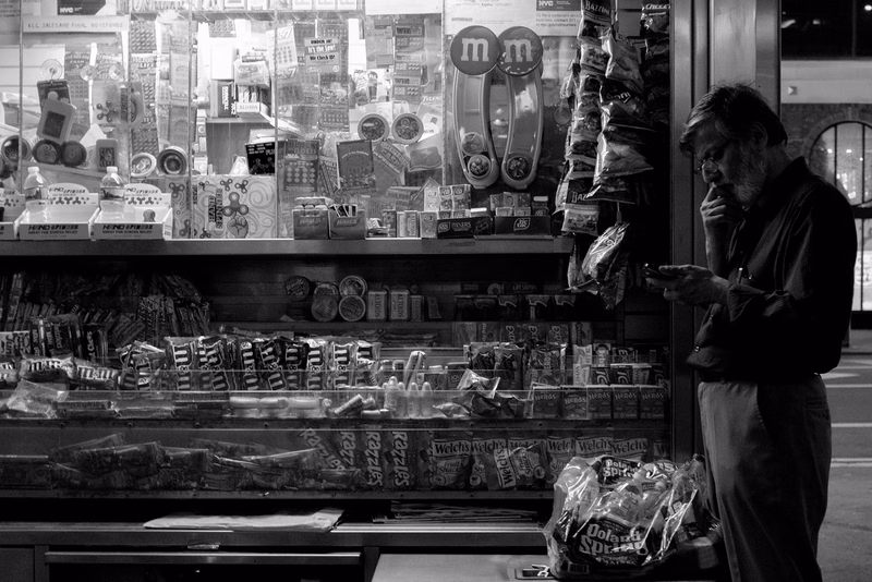 A man stands in a candy store aisle, looking at shelves stocked with various sweets and M&M candies.