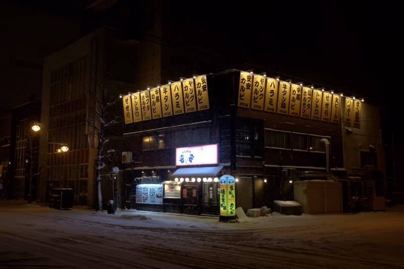 A snowy night in Sapporo, Japan, with a building and signage.