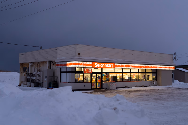 A small convenience store in a snowy, rural area with a flat roof and large windows.