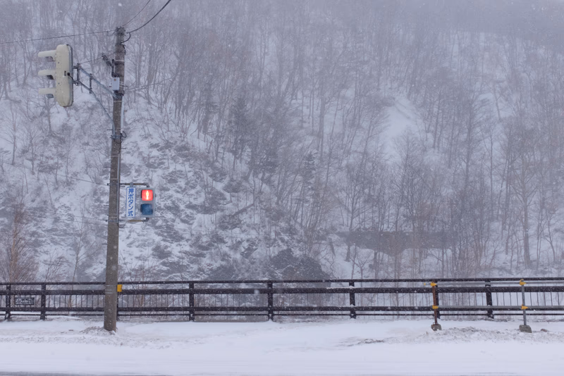 A wintery scene near Kamikawa, Hokkaido, Japan, with a snowy landscape and a railway crossing.