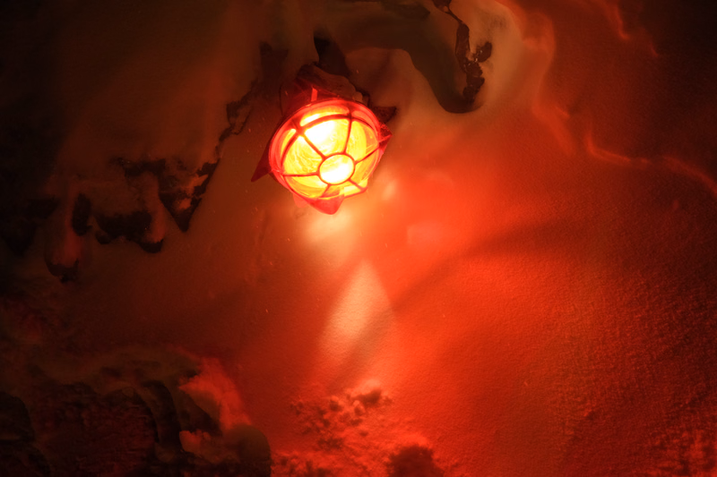 A glowing red lantern hangs in a dark, misty environment, casting a warm, intense light.
