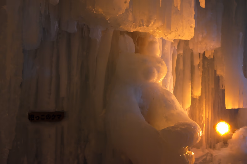 A photograph of an ice sculpture in a cave illuminated by a warm light