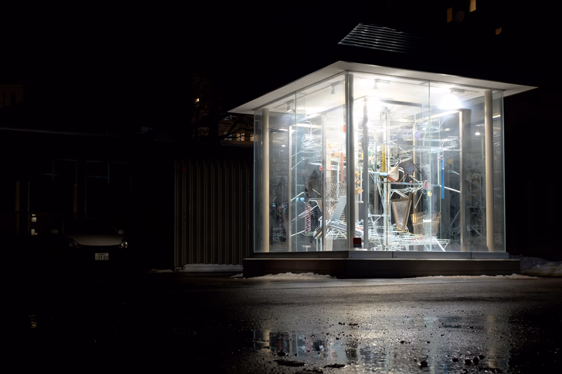 A nighttime view of a storefront with a glass display showcasing an illuminated interior.