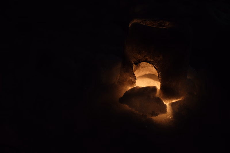 Glowing embers and firelight illuminate the dark interior of a structure.