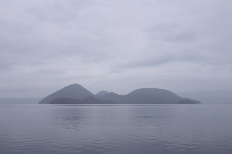 A serene seascape with calm waters and a series of islands in the background.