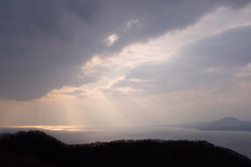 A serene landscape with a dramatic sky and a mountain range in the distance.