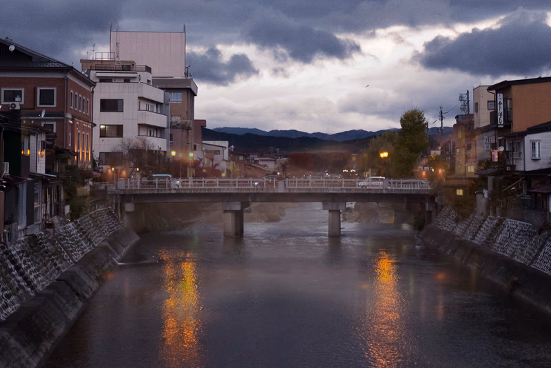 A photo of a river running through a city, with a bridge in the foreground and buildings on both sides.