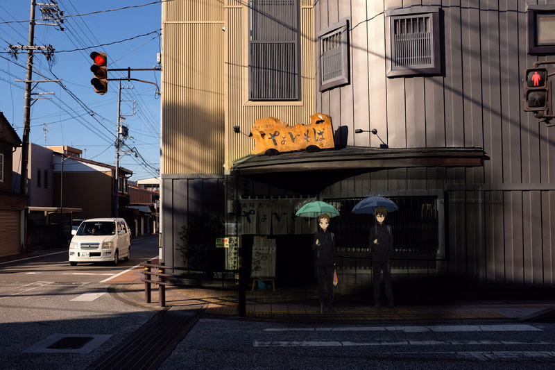 Two people stand under an awning in front of a modern building, with a traffic light visible on the left.