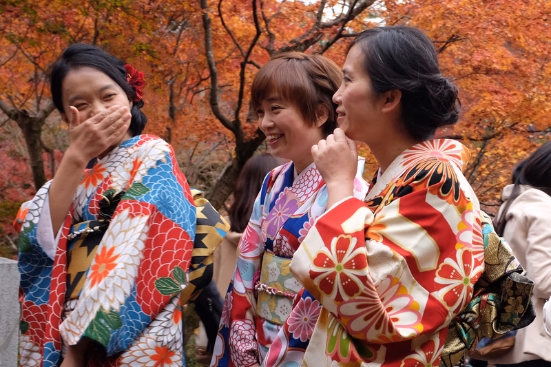 A group of people in traditional kimonos enjoying the autumn leaves in a picturesque setting.