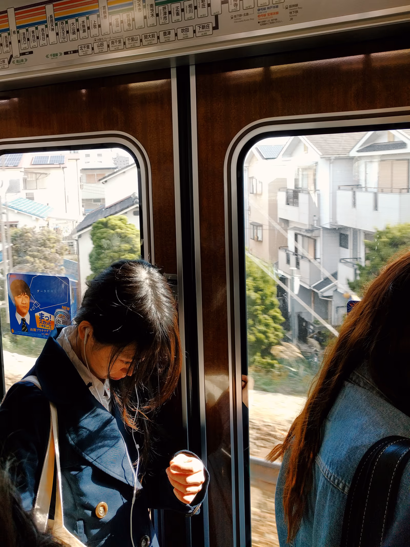 A woman standing by a train window, looking at the sunlight.