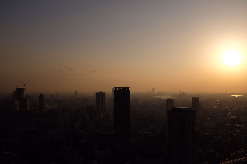 A silhouette of a city skyline against a bright orange and yellow sunset.