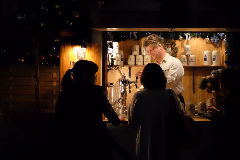 A nighttime scene at a coffee shop where people are interacting and enjoying their drinks.