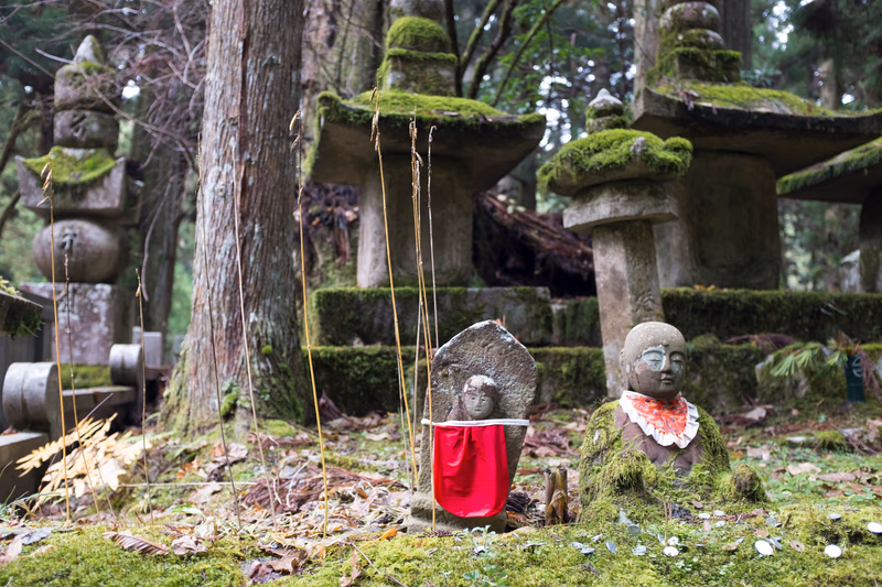 A serene forest scene with a stone statue and a wooden structure covered in moss, surrounded by other nature-inspired elements.
