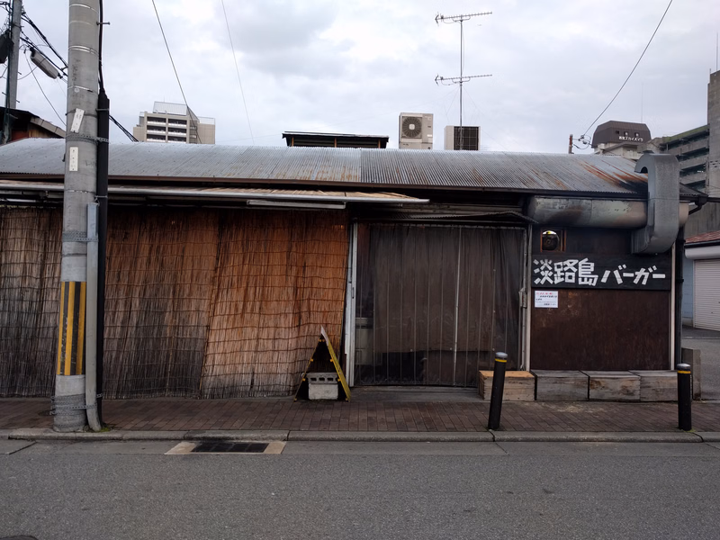 A small shop with a corrugated metal roof displays a sign that reads "淡島バーガー" (Awashima Burger).