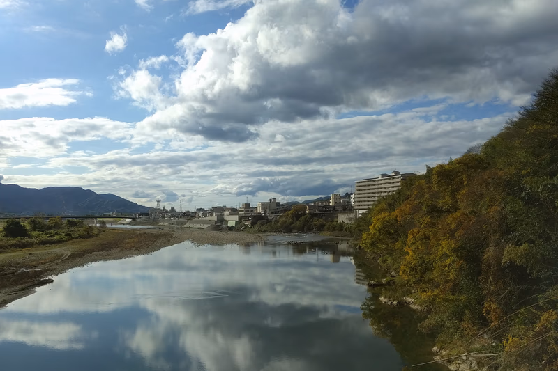 A serene river in the heart of a city surrounded by mountains, with a modern cityscape in the background.
