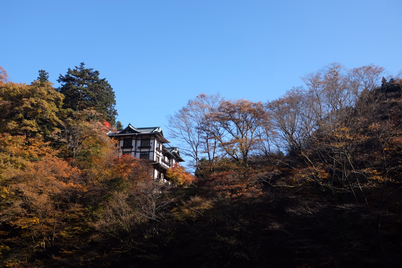A beautiful autumn scene with a traditional Japanese building surrounded by colorful trees.