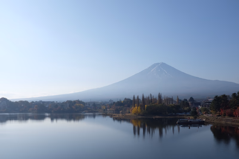 A serene lake reflecting the majestic silhouette of Fuji-yoshida on a clear day