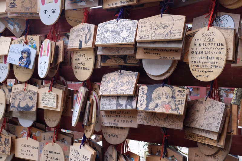 A collection of numerous handmade paper cards and decorations are strung together on a wooden display, some featuring drawings and text like "2022".
