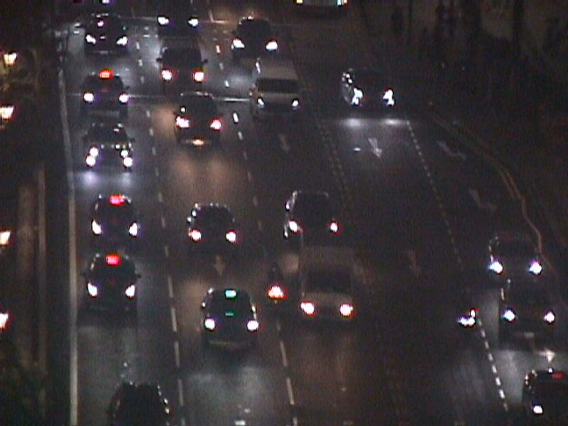 A nighttime view of heavy traffic on a multi-lane road with many car headlights visible.