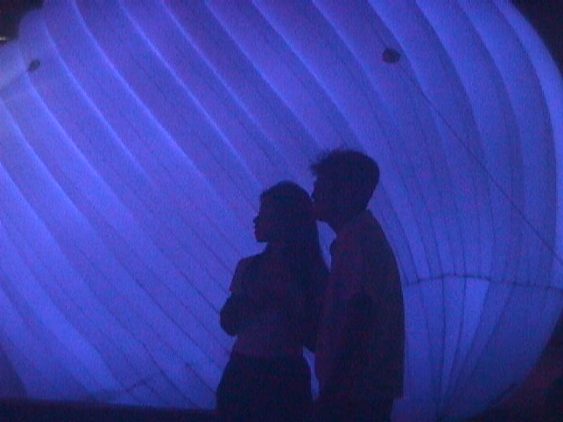 Two people are visible as dark silhouettes against the bright, curved interior of a large tent.