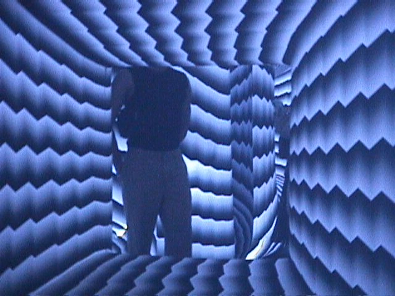 An abstract image of a tunnel with repeating, undulating blue and white light patterns receding into the distance.