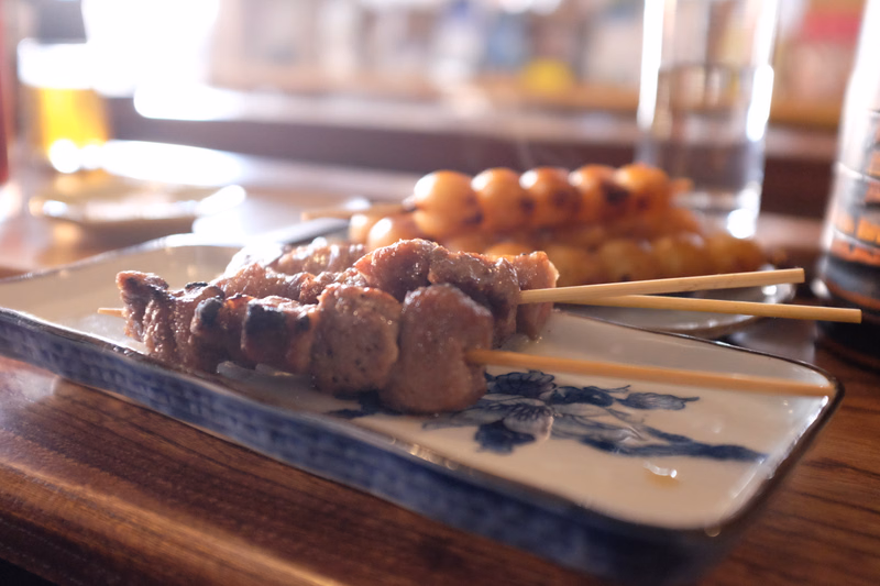 Grilled meat skewers are served on a rectangular blue and white patterned plate in a restaurant setting.