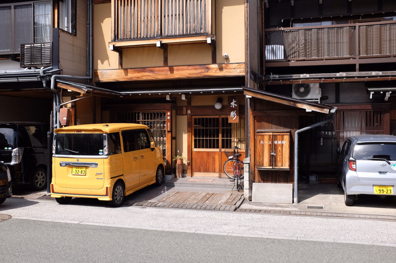 A yellow van is parked in front of a traditional wooden shopfront with a sign that reads "木影".