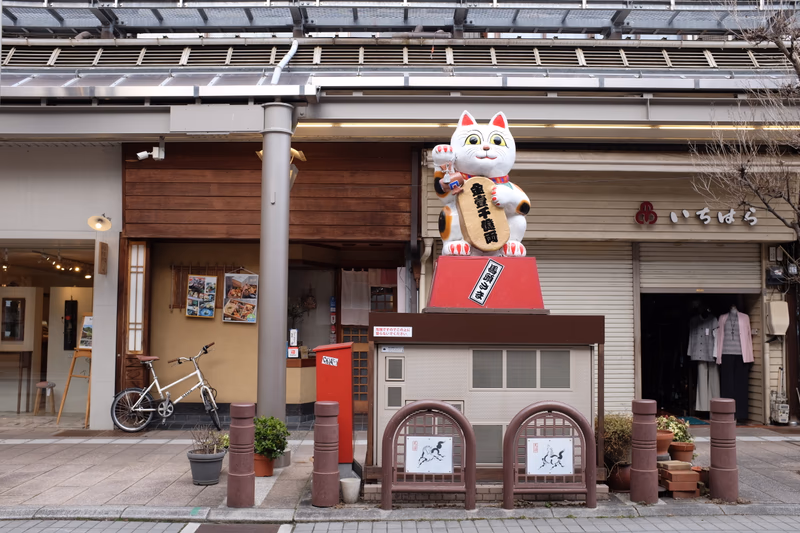 A cat statue in front of a building in a small town in Japan.