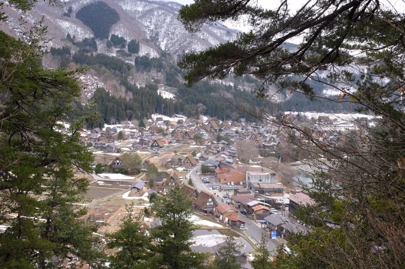A view of a small town nestled in a valley surrounded by snow-dusted mountains during winter.