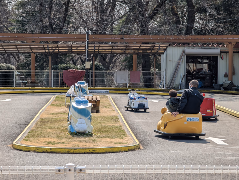 A man and a woman are riding a small ride car in an amusement park.