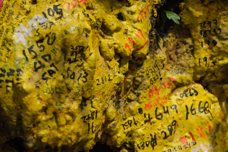 Yellowish rock covered in various markings and graffiti, including numbers like "1552" and "2812".